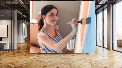 Happy smiling woman painting interior wall of new house. Happy smiling woman Wall mural