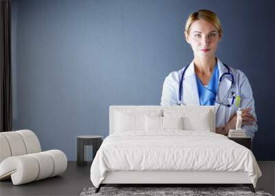 Portrait of young woman doctor with white coat standing in hospital. Wall mural