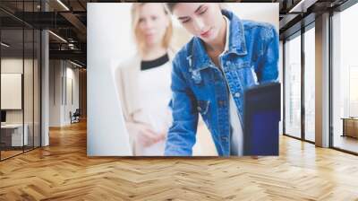 Two young woman standing near desk with instruments, plan and laptop. Wall mural