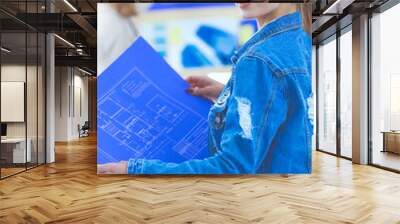 Two young woman standing near desk with instruments, plan and laptop. Wall mural