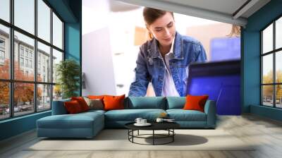 Two young woman standing near desk with instruments, plan and laptop Wall mural