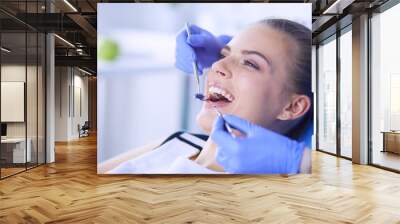 Young Female patient with open mouth examining dental inspection at dentist office. Wall mural