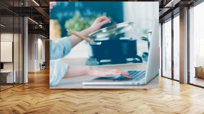 young woman in kitchen with laptop computer looking recipes, smiling. food blogger concept Wall mural