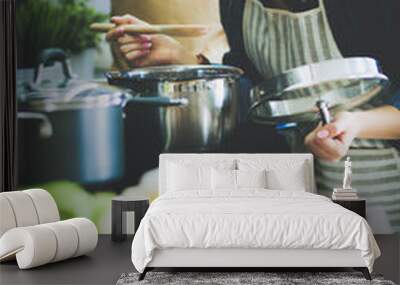 Young woman standing by the stove in the kitchen . Wall mural