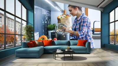 Young woman standing by the stove in the kitchen Wall mural