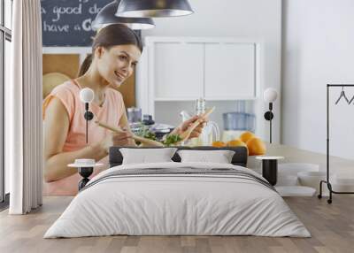 Happy young cook girl preparing food from greens Wall mural