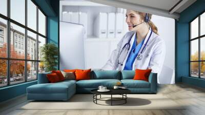 Portrait of a happy smiling young doctor in headset in office Wall mural