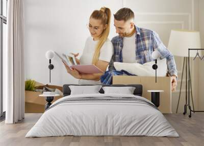 Portrait of happy couple looking at laptop computer together sitting in new house, surrounded with boxes Wall mural