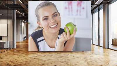 Young beautiful smiling girl with a green apple in hands Wall mural