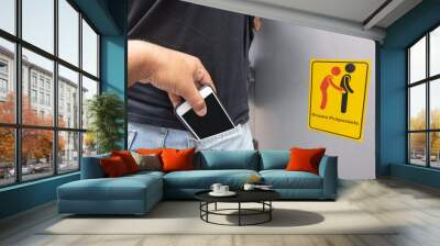 Thief stealing mobile phone from back pocket of a woman with beware pickpockets sign symbol background Wall mural