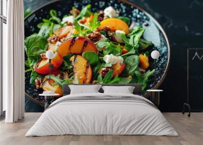 A fresh salad with grilled peaches, greens, and nuts served on an elegant black plate Wall mural