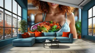 A young woman presenting a colorful bowl of mixed salad with a variety of vegetables Wall mural