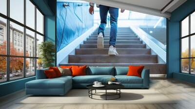 An individual in casual attire ascending a set of indoor stairs, conveying motion and progress Wall mural