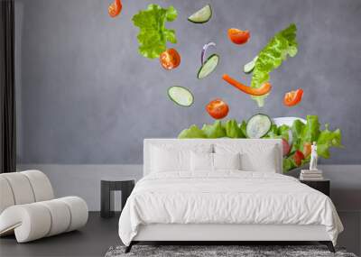 Levitation of vegetarian green salad made of green leaf, cherry tomatoes, cucumbers, onion and pepper Wall mural