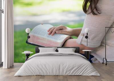 Christian woman sitting outside having quiet time and reading Bible Wall mural