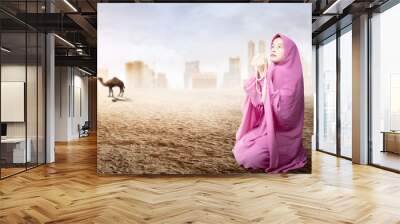 Asian Muslim woman in veil sitting and praying with prayer beads on her hands Wall mural