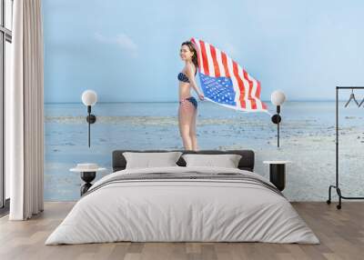 Asian sexy girl in bikini of american flag holding a waving american flag on the beach Wall mural