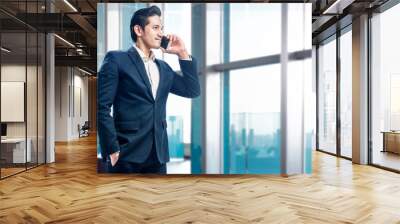 Handsome asian businessman standing while talking on the cellphone Wall mural