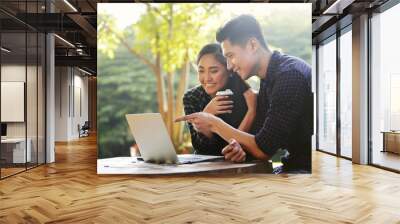 Happy asian couple looking at something on a laptop Wall mural