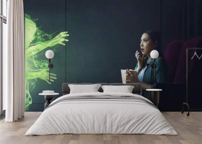 Shocked asian woman watching scary movie with popcorn Wall mural