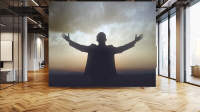 Silhouette of businessman raised hands and praying to god Wall mural