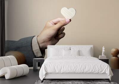 The businessman's hand shows a wooden heart with a rate symbol Wall mural