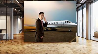 Young business man calling by phone when walking to the plane Wall mural