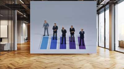 Mini business men standing on paper with blua and purple lines printed on it Wall mural