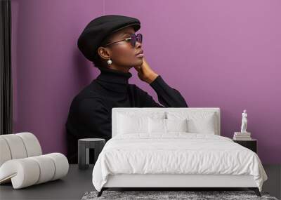 Stylish portrait of a person in a black outfit and hat set against a purple background highlighting modern fashion elegance and contemporary design Wall mural