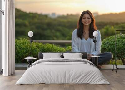 Young woman meditating in a park at sunset with soft golden light filtering through the trees symbolizing mindfulness inner calm and harmony with nature in a serene setting Wall mural