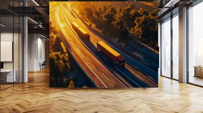 Aerial view of two cargo trucks driving through highway at sunset. Wall mural