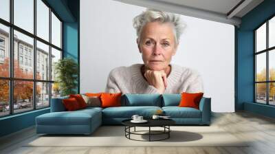 Medium shot portrait photography of a woman in her 50s visibly in discomfort and fatigue from an autoimmune disease like lupus wearing a cozy sweater against a white background  Wall mural