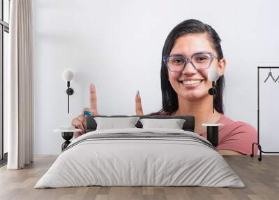 latina woman with smiling glasses on white background pointing with fingers  Wall mural