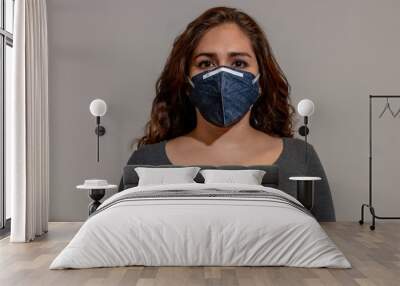 young woman in medical face protection mask indoors on white background Wall mural