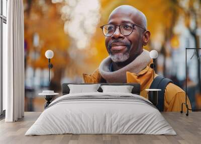 Middle-aged black man standing seriously on a street surrounded by autumn foliage in casual attire Wall mural