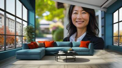 Smiling middle aged Asian female realtor standing outdoors Wall mural