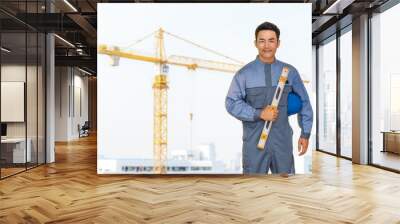 Portrait of engineer holding the blue helmet safety on construction site with crane background Wall mural