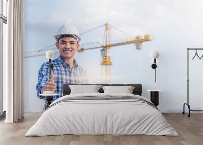 Portrait of engineer wear a white safety helmet and hold the blueprint with construction site and crane background. He has smile because his project were success. Wall mural