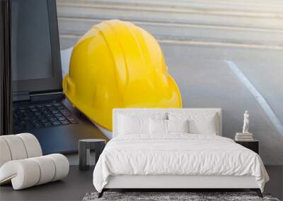 The yellow safety helmet with the blueprint and laptop at construction site Wall mural