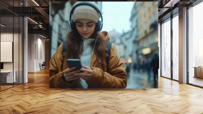 Enjoying her digital music, female traveler wears headphones while checking her phone on rainy street. cozy atmosphere reflects her relaxed mood Wall mural