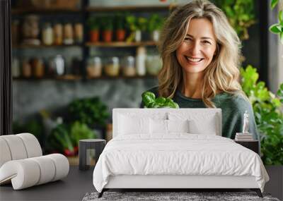 Smiling middle aged woman making vegetarian smoothie on the kitchen at home Wall mural