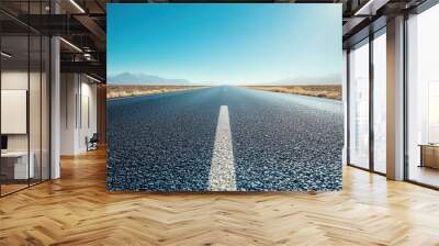 wide asphalt highway stretches into clear blue horizon, surrounded by vast open land and distant mountains. scene evokes sense of freedom and adventure Wall mural