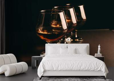 three glasses with cognac in a row on a dark background Wall mural