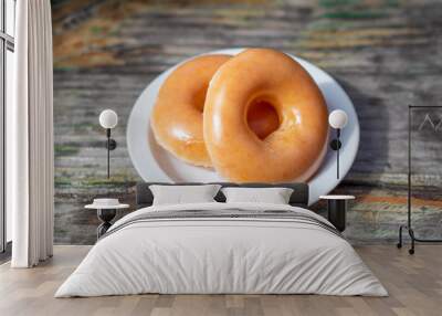 Two delicious donuts on a white dish on wooden table. Wall mural