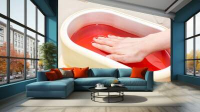 The process of paraffin therapy of a female hand is shot close up in a beauty salon. Wall mural