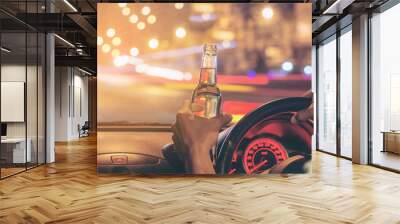 Drunk young man driving a car with a bottle of beer. Don't drink and drive concept. Driving under the influence. DUI, Driving while intoxicated. Wall mural