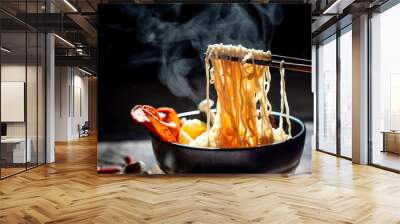 Hand uses chopsticks to pickup tasty noodles with steam and smoke in bowl on wooden background, selective focus. Asian meal on a table, junk food concept Wall mural