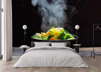 The steam from the vegetables carrot broccoli Cauliflower in a black bowl, a steaming. Boiled hot Healthy food on table on black background,hot food and healthy meal concept Wall mural