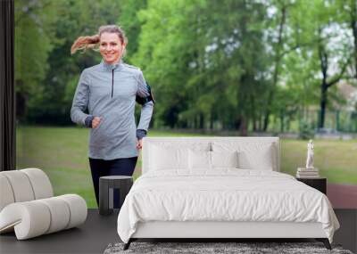 Athletic woman running on track with smart phone app, fitness lifestyle Wall mural