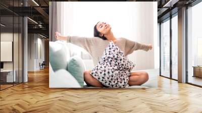 Cute asian young woman sitting on sofa with pillow at home Wall mural